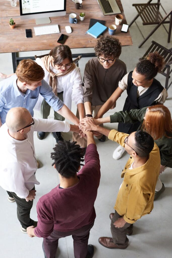 pexels photo 3184423 A diverse group of professionals joins hands in a team-building exercise indoors.