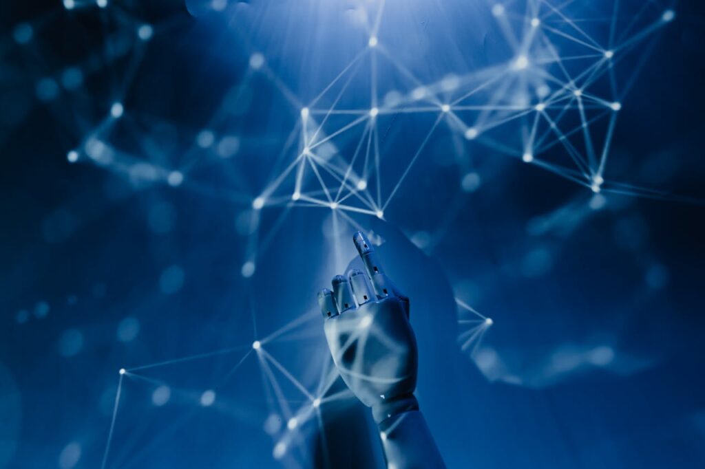 pexels photo 8386440 A robotic hand reaching into a digital network on a blue background, symbolizing AI technology.